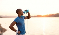 A man drinks water on a sunny morning.