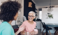 Two neighbors chat over a cup of coffee.