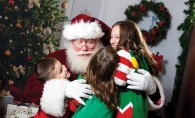Santa hugs a group of children at a Custom One Charities event.