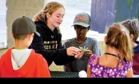 A camp counselor guides children through an activity at Camp Carver.