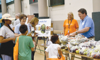 Food shelf volunteers chat with families about healthy fruit and veggies at a local gathering.