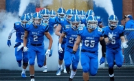 The Woodbury High School football team charges onto the field before a game.