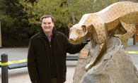 Eric Galler stands next to a statue of a leopard.