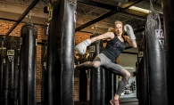 Sarah Krotz, a coach at TITLE Boxing Club Woodbury, kicks a punching bag.