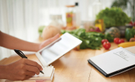 A person plans a healthy menu using a tablet and a notebook.