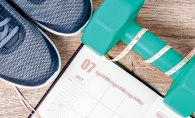 Exercise shoes, a free weight and a schedule tracking fitness goals.