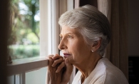 Woodbury Senior Living An elderly woman looks out a window.