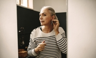 A woman tries on earrings in a mirror.