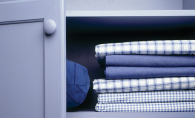 A pillow and sheets sit organized on shelves, ready for tidying up before a downsizing move.