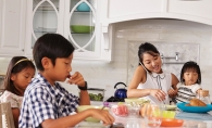 A mother talks on the phone while feeding her three children