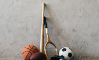 A variety of sports equipment: basketball, football, baseball bat, ball and glove, tennis racket, soccer ball
