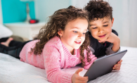 Two children look at a tablet during their screen time.