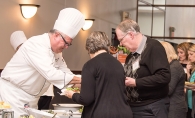 A chef prepares food for two guests at the Woodbury Community Foundation's Chef Fest.