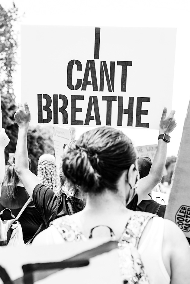 Someone at a memorial for George Floyd holds an "I can't breathe" sign