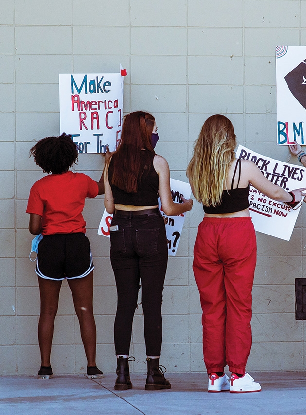 Teenagers hold protest signs.