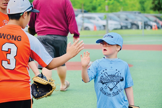 Two players high-five at an East Metro Miracle League game