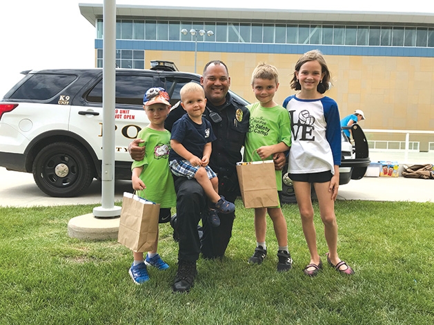 Kids pose with a police officer at Half Pint Safety Camp