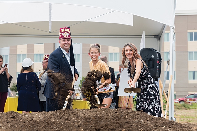 Three people break ground at the Shriners Healthcare for Children clinic in Woodbury