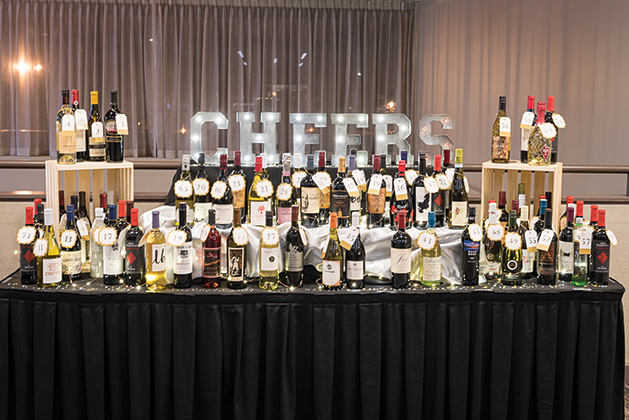 A table filled with wine and a light-up Cheers sign at the Woodbury Chamber Awards Gala.