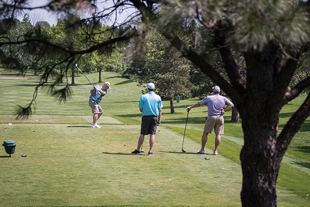 Three golfers tee off at the 33rd Annual Woodbury Area Chamber of Commerce golf tournament.