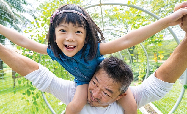 A daughter sits on her father's shoulders.