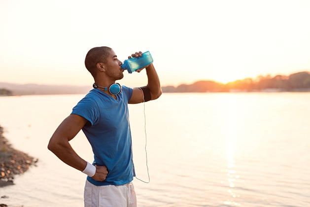 A man drinks water on a sunny morning.