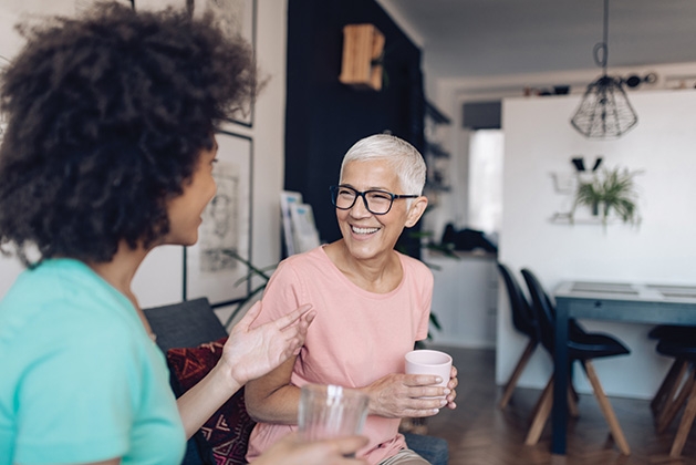 Two neighbors chat over a cup of coffee.