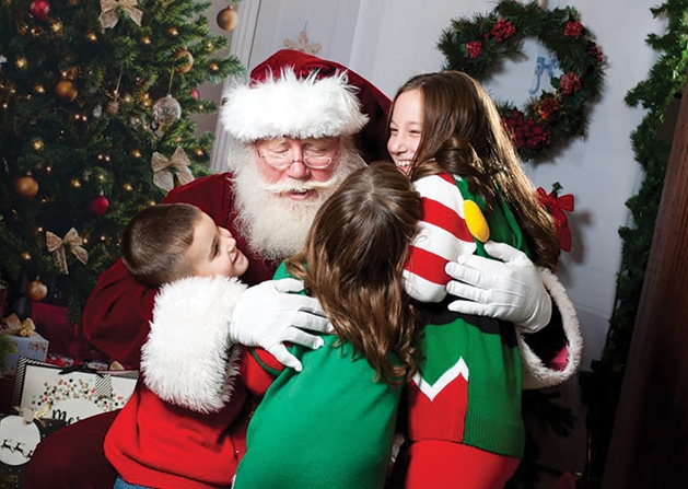 Santa hugs a group of children at a Custom One Charities event.