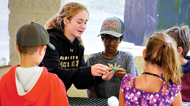A camp counselor guides children through an activity at Camp Carver.