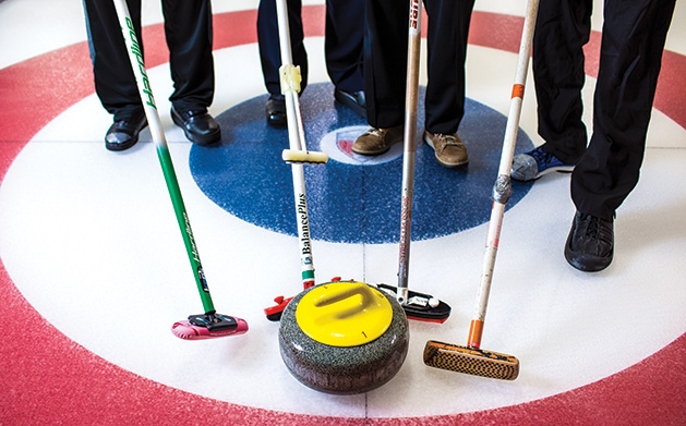 Four curling brooms and a stone at the St. Croix Curling Center