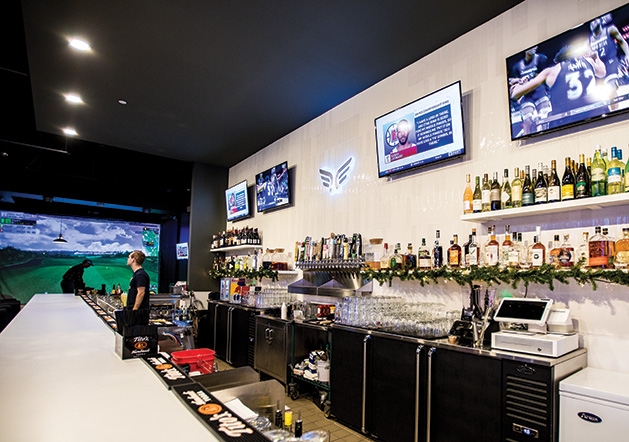 The bar at Birdi Golf, with a golf simulation station in the background.