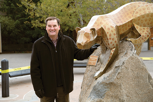 Eric Galler stands next to a statue of a leopard.