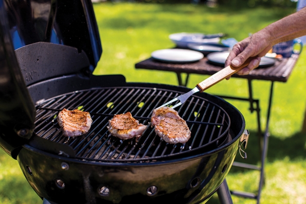 Hand flipping porkchops on the grill