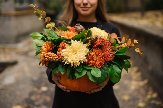 A woman holding an autumnal bouquet.