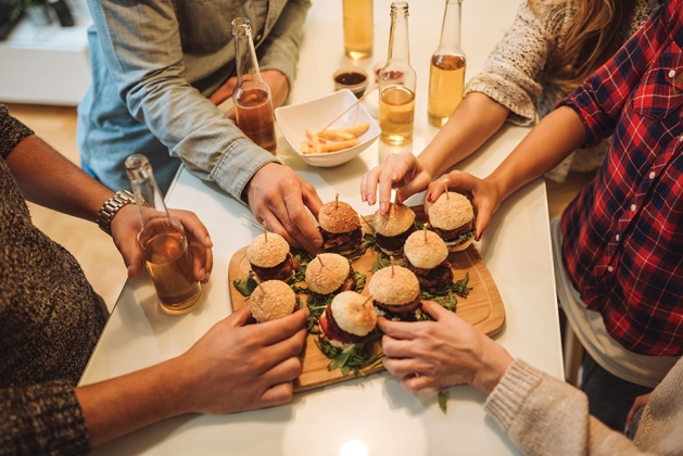 People grabbing burgers at a Super Bowl party.