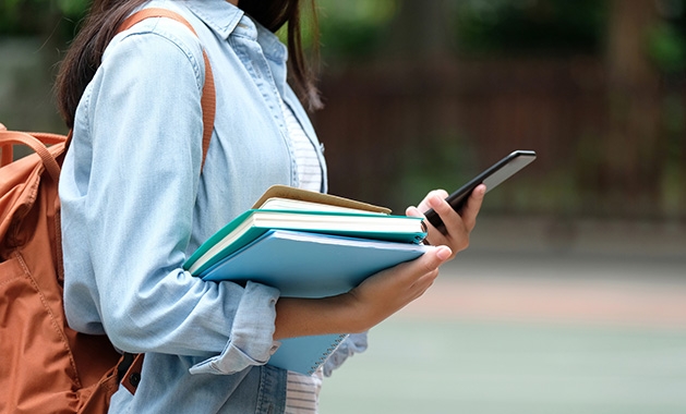 A girl goes to back to school with her backpack and books.