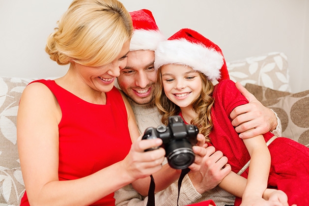 A mother, father and daughter review their family holiday photos
