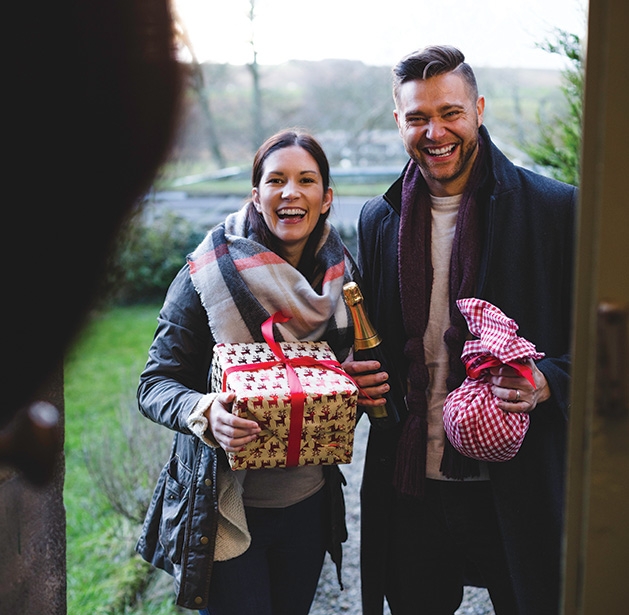 A couple brings wine and presents to a family Christmas gathering.