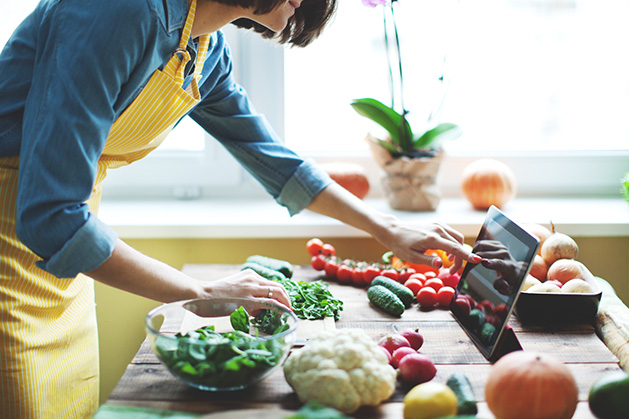 A woman cooks a solo meal while reading a recipe off of an iPad.