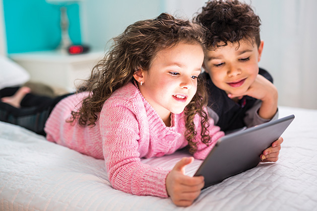 Two children look at a tablet during their screen time.