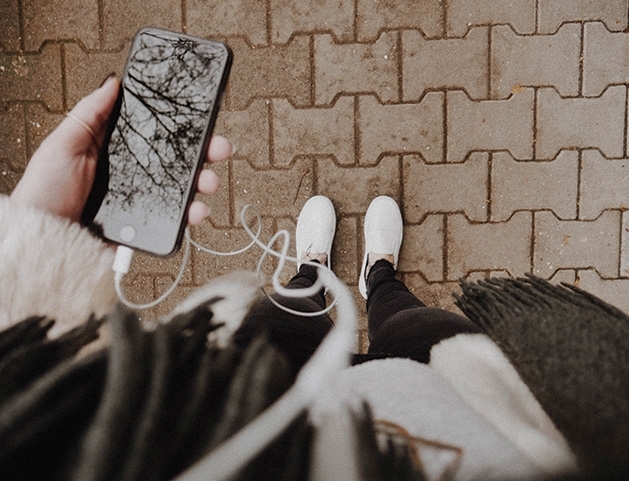 A person looks down at their phone while listening to a podcast.