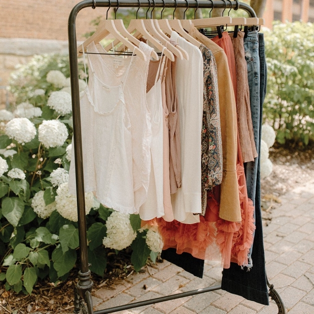 Clothing rack full of clothes in warm, neutral tones.