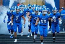 The Woodbury High School football team charges onto the field before a game.