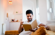 Man reading book at home in living room