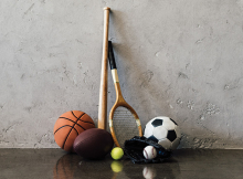 A variety of sports equipment: basketball, football, baseball bat, ball and glove, tennis racket, soccer ball