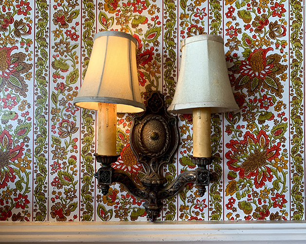 Two lamps on a wallpapered wall.