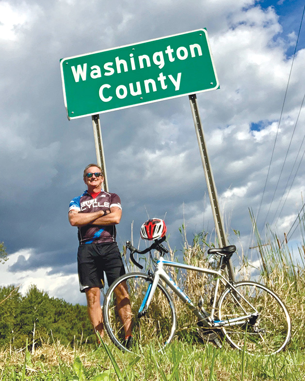 Terry Stille stands with his bike near a Washington County road sign.