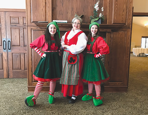 Three women clad in Christmas attire pose for a photo at the HealthEast Sports Center Holiday Exhibition and Party