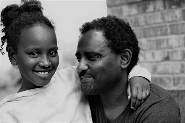 A father and daughter smile for the camera.