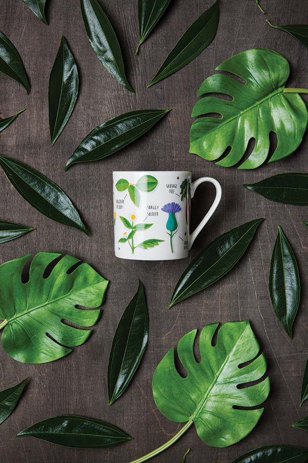 A mug from Patina surrounded by leaves.